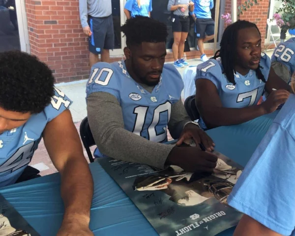 Junior linebacker Andre Smith (10) signs a UNC football poster Saturday at the "Meet the Heels" event.