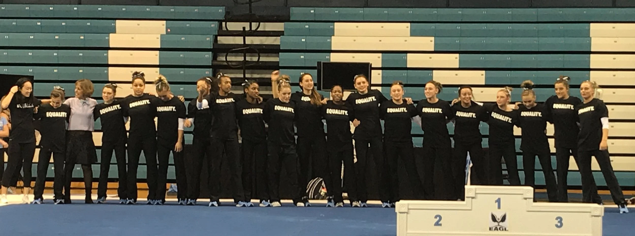 UNC gymnasts wearing “EQUALITY.” T-shirts celebrate a win over Temple University, and inclusion and diversity, with Chancellor Carol Folt | Photo by Bryce Lapping