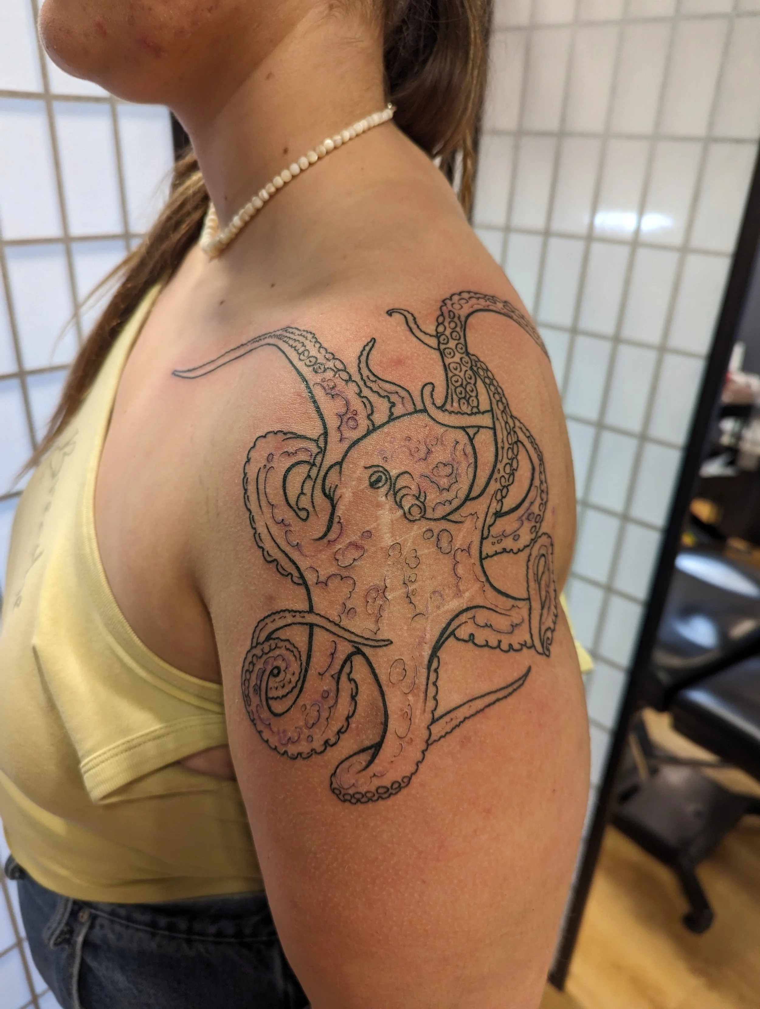 Tattoo of an octopus on a woman's upper arm and shoulder.