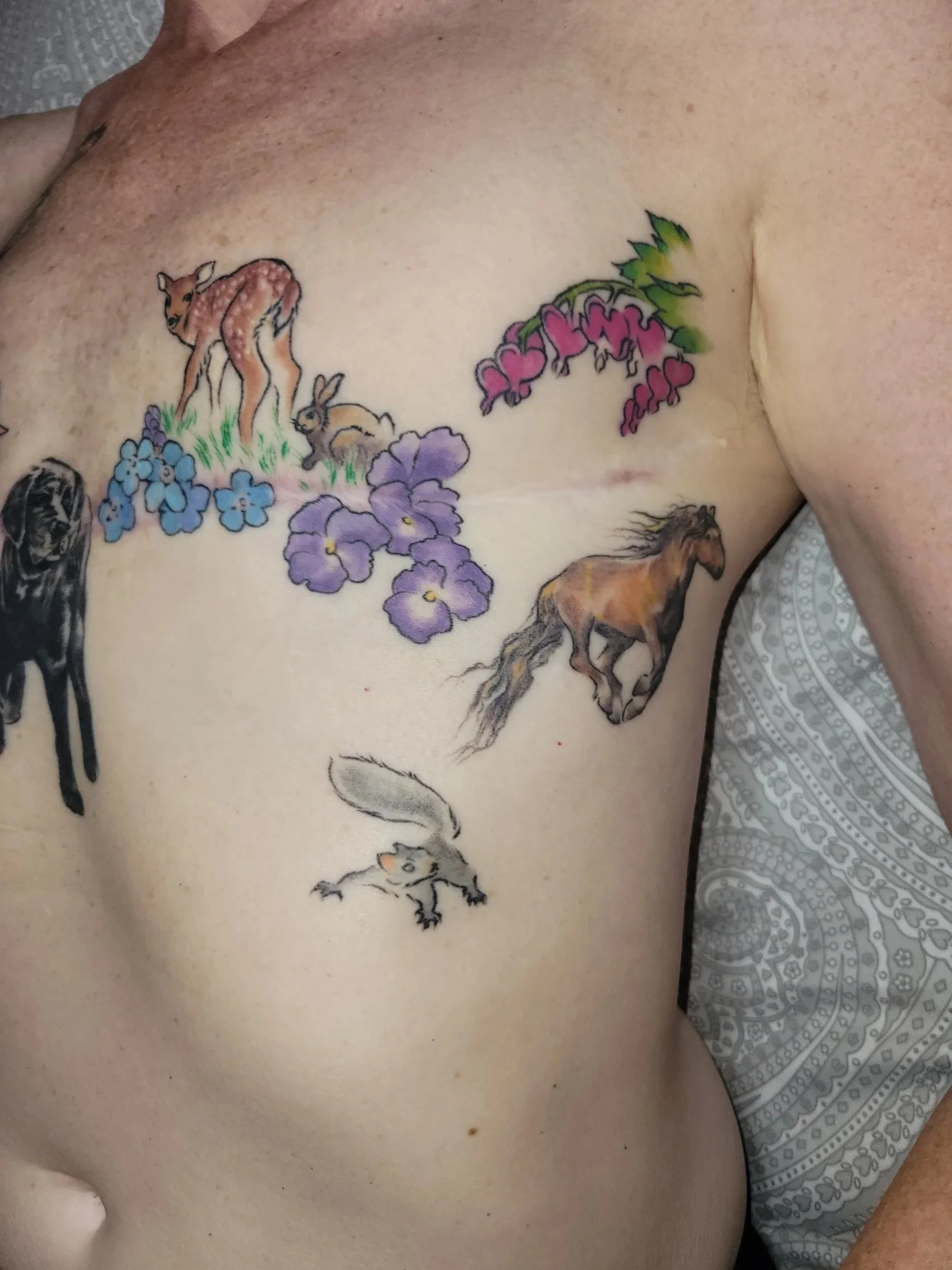 Tattoo of various animals and flowers on a person's chest, including a deer, rabbit, horse, black dog, and different colored flowers.