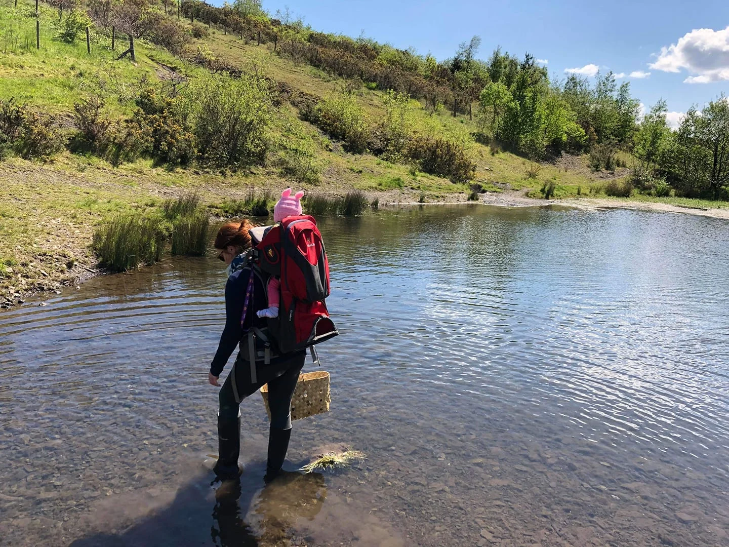 Mother with child in backpack by pond
