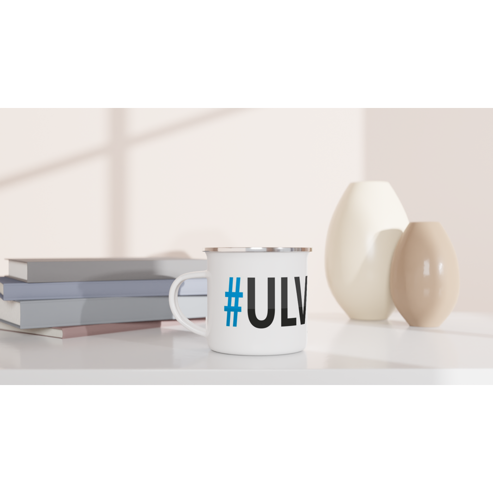 The picture shows a left side view of the 12oz white enamel mug "#ULVÖN Höga Kusten" from the series HIKING #TAGMUG™ on a desktop
