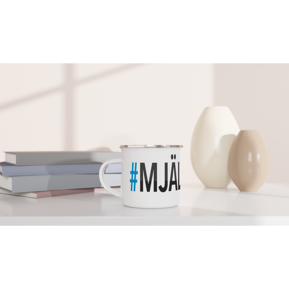 The picture shows a left side view of the 12oz white enamel mug "#MJÄLTÖN Höga Kusten" from the series HIKING #TAGMUG™ on a desktop
