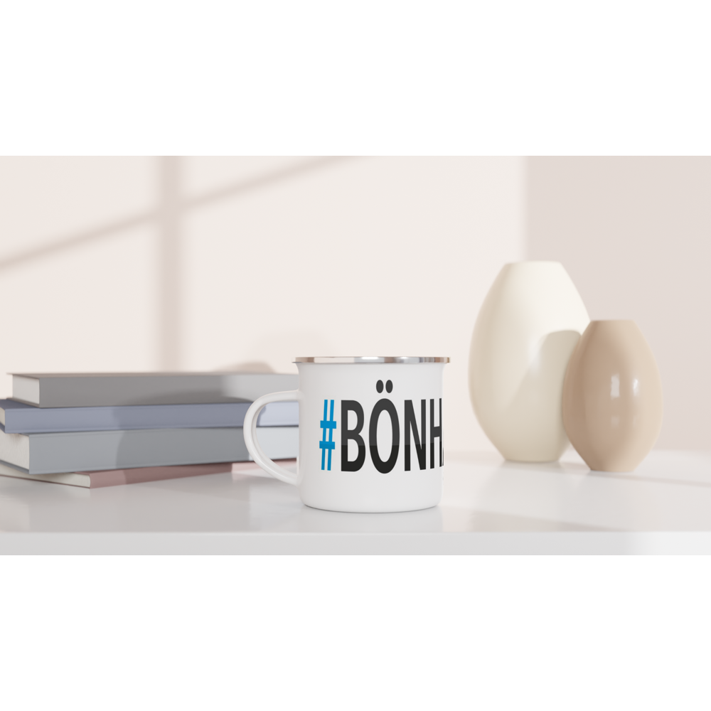 The picture shows a left side view of the 12oz white enamel mug "#BÖNHAMN Höga Kusten" from the series HIKING #TAGMUG™ on a desktop