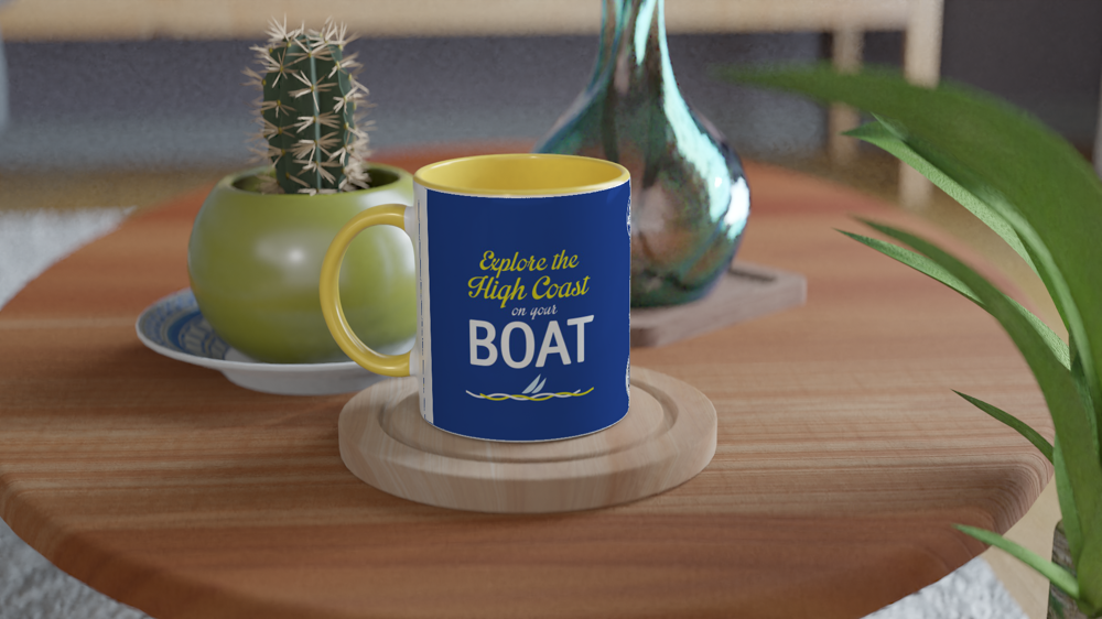 The picture shows a left side view of the 11oz ceramic mug "EXPLORE THE HIGH COAST” from the series HIGH COAST SAILOR #TAGMUG™ with yellow color inside on a contemporary kitchen table