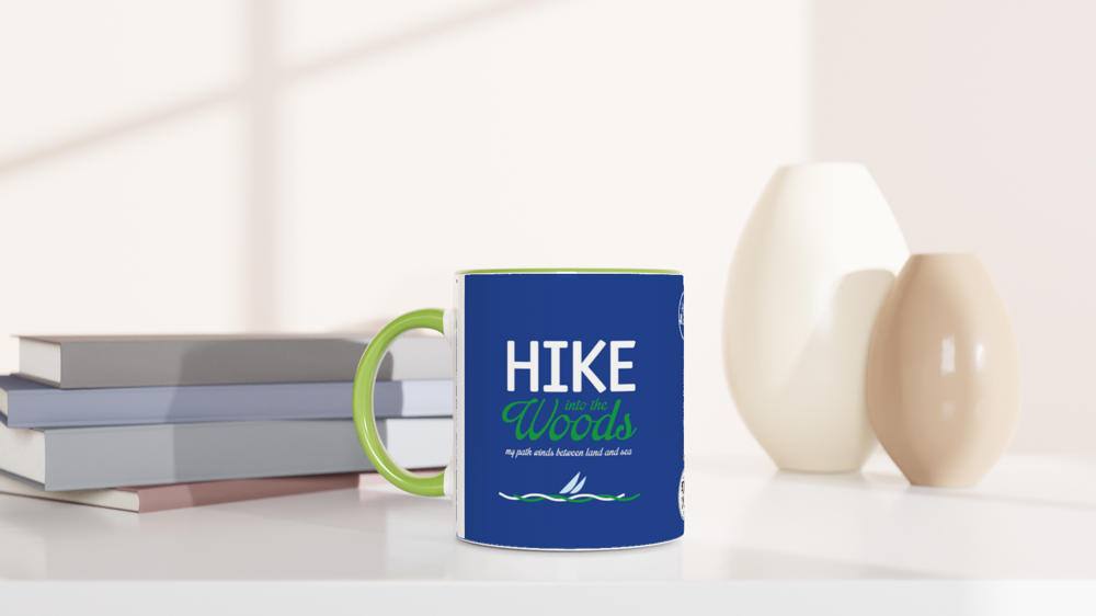 The picture shows a left side view of the 11oz ceramic mug "HIKE INTO THE WOODS" from the series HIGH COAST SAILOR #TAGMUG™ with green color inside on a desktop