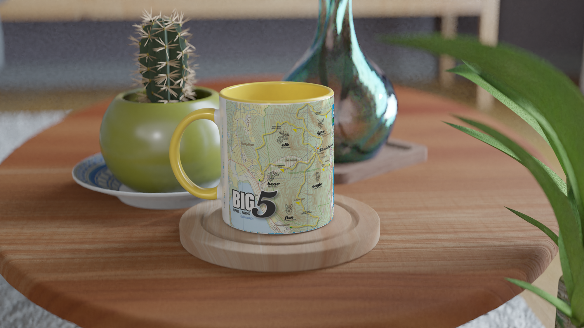 It shows a left side view of the 11oz ceramic mug "SKULEBERGET ELK PATH” from the series ““SKULE BIG5" #TAGMUG™ with yellow color inside on a contemporary kitchen table