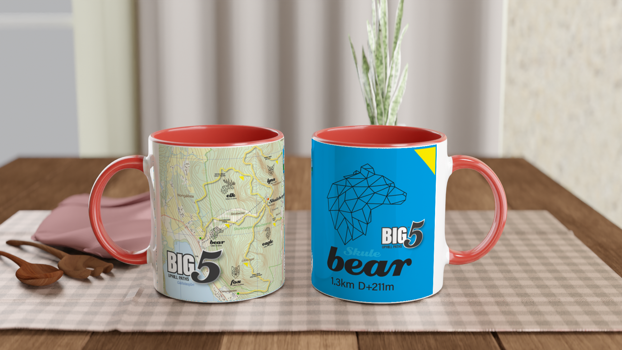 The picture shows the left and right side view of two 11oz ceramic mugs "SKULEBERGET BEAR PATH" from the series “SKULE BIG5" #TAGMUG™ with red color inside