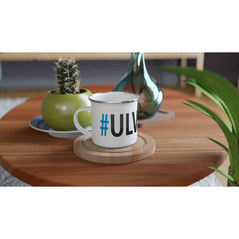 The picture shows a left side view of the 12oz white enamel mug "#ULVÖN Höga Kusten" from the series HIKING #TAGMUG™ on a contemporary kitchen table