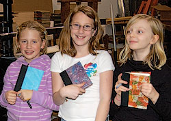 Three young bookmakers hold their finished, colorful hand sewn books.
