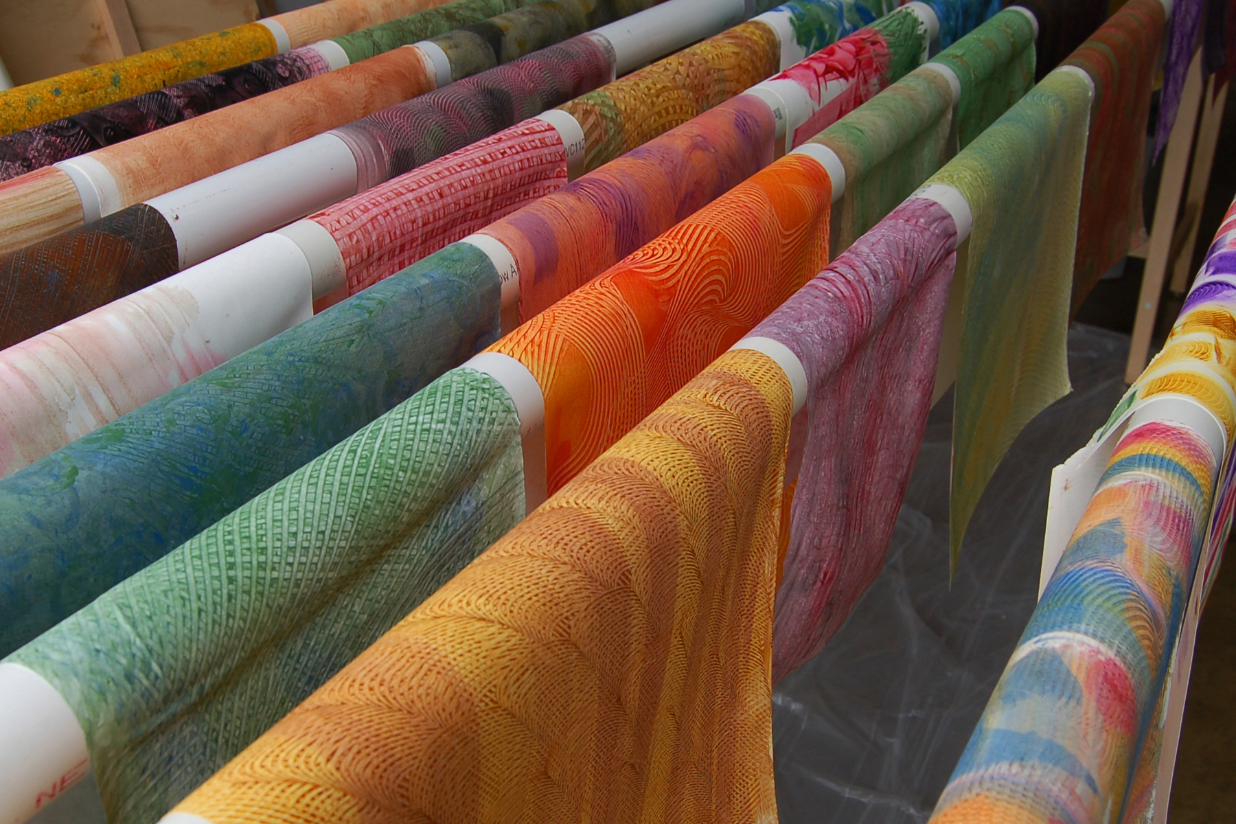 This bright field of freshly painted paste paper is hanging to dry for a while before being turned into colorful folio covers for certificates.
