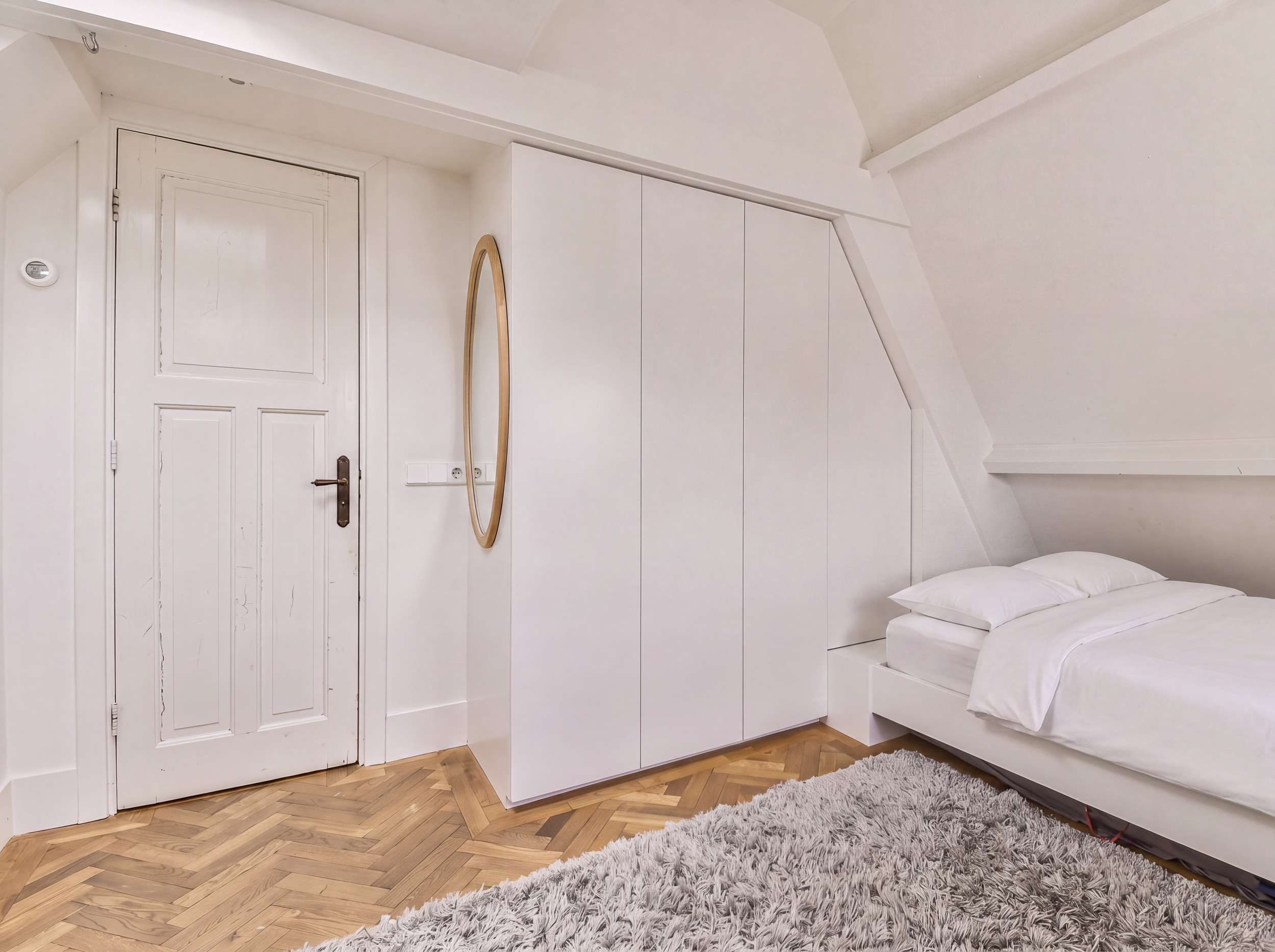 Built-in wardrobe and bed under sloped roof