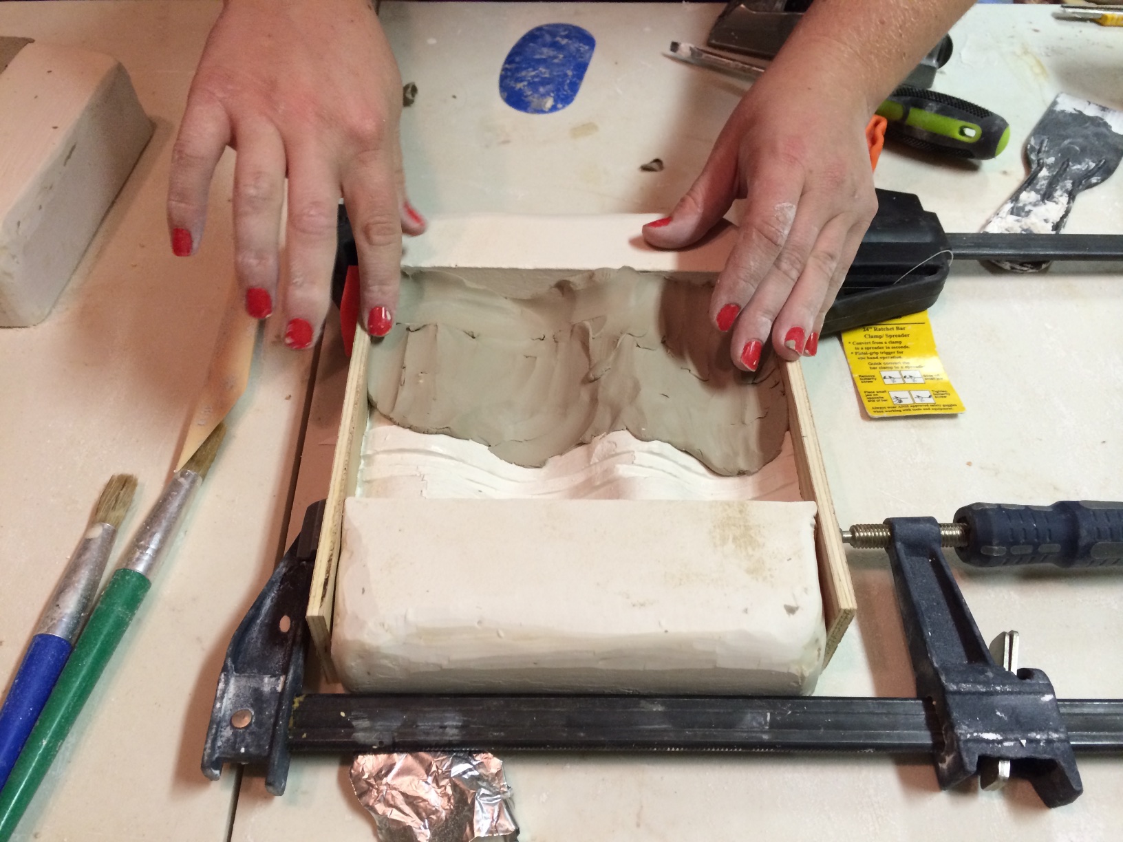 The modified mold required wood sides to be clamped on, completing the negative shape. Here, clay is being pressed in to the mold.