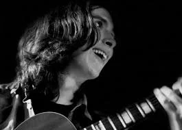 Man smiling while playing guitar
