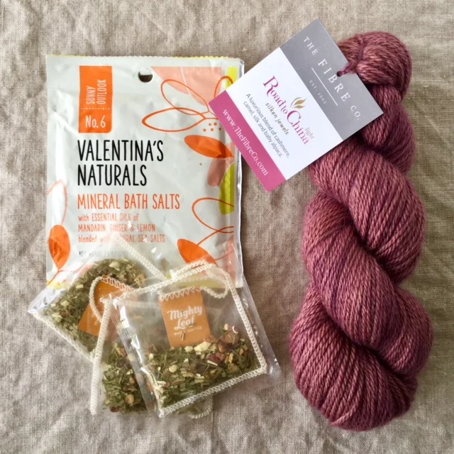 A skein of the Fibre Co. Road to China Light in the Carnelian colorway, Mighty Leaf Ginger Twist Tea, and Valentina’s Naturals Sunny Outlook Mineral Bath Salts