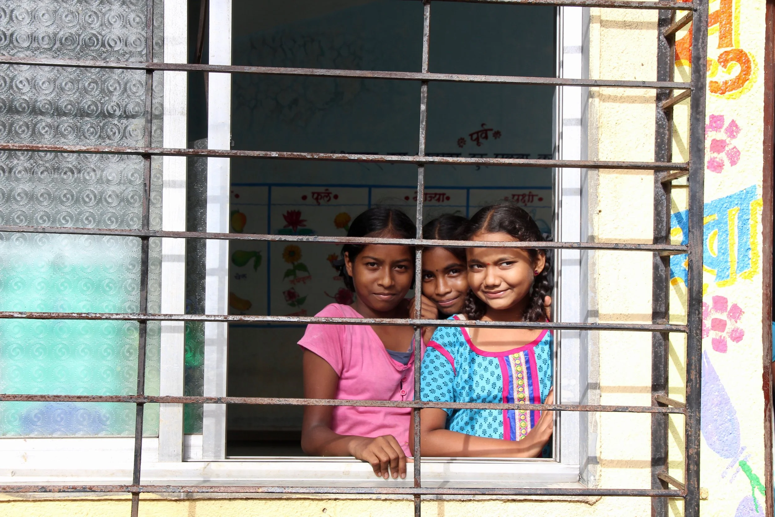 Four junior-school girls giggle at the camera. Today I spent the day helping a local company and non-profit distribute school supplies to schools in the Palghar district. 
