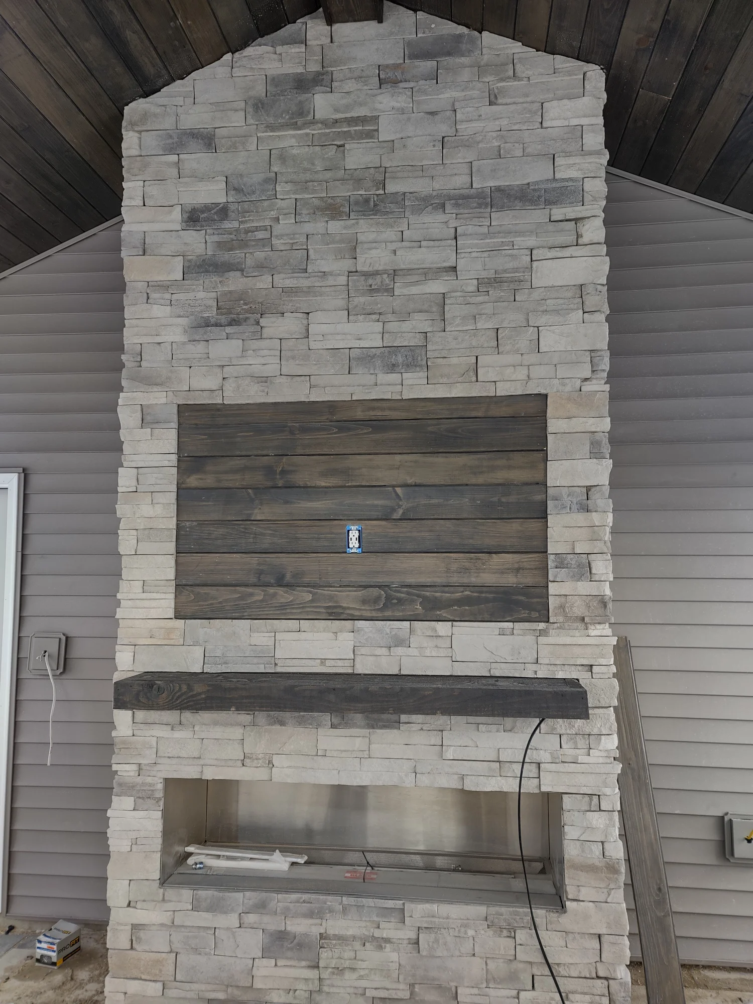 Natural stone accent wall Syracuse NY with reclaimed wood mantel and TV mount