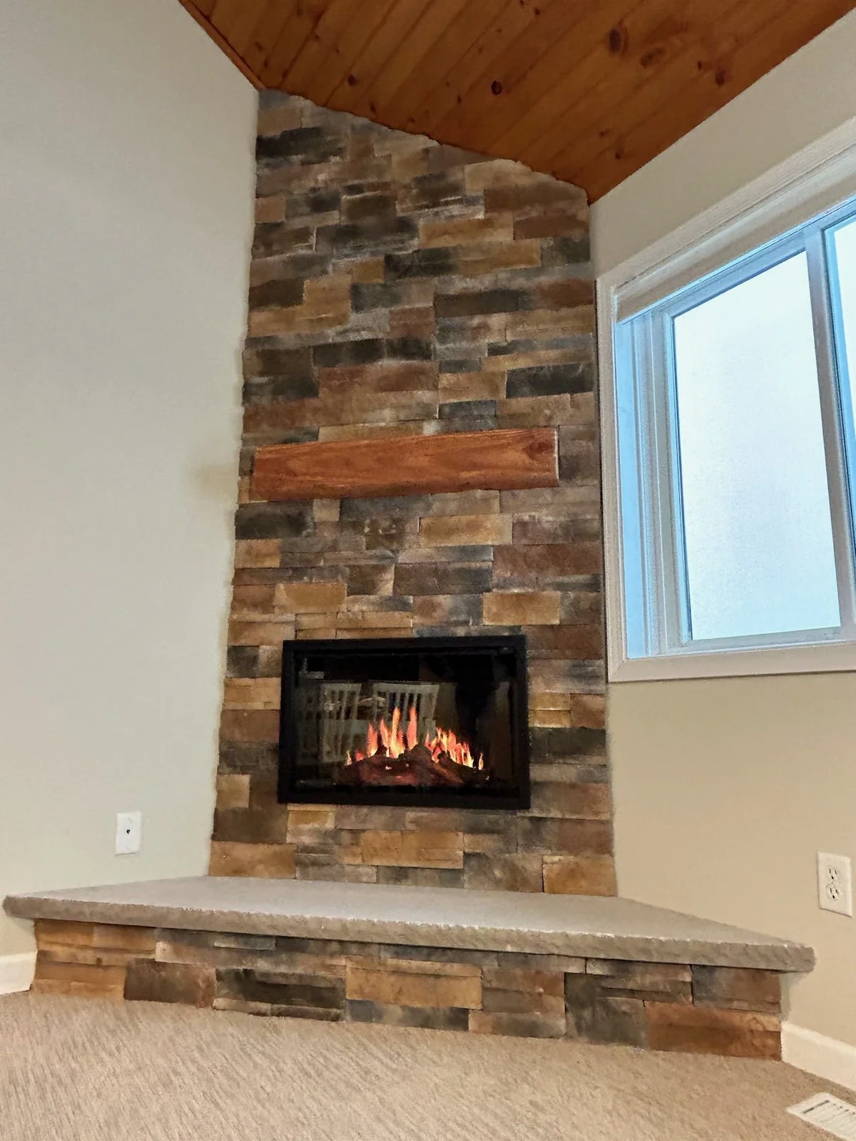 Stone veneer fireplace installation Syracuse NY stacked stone with wood mantel