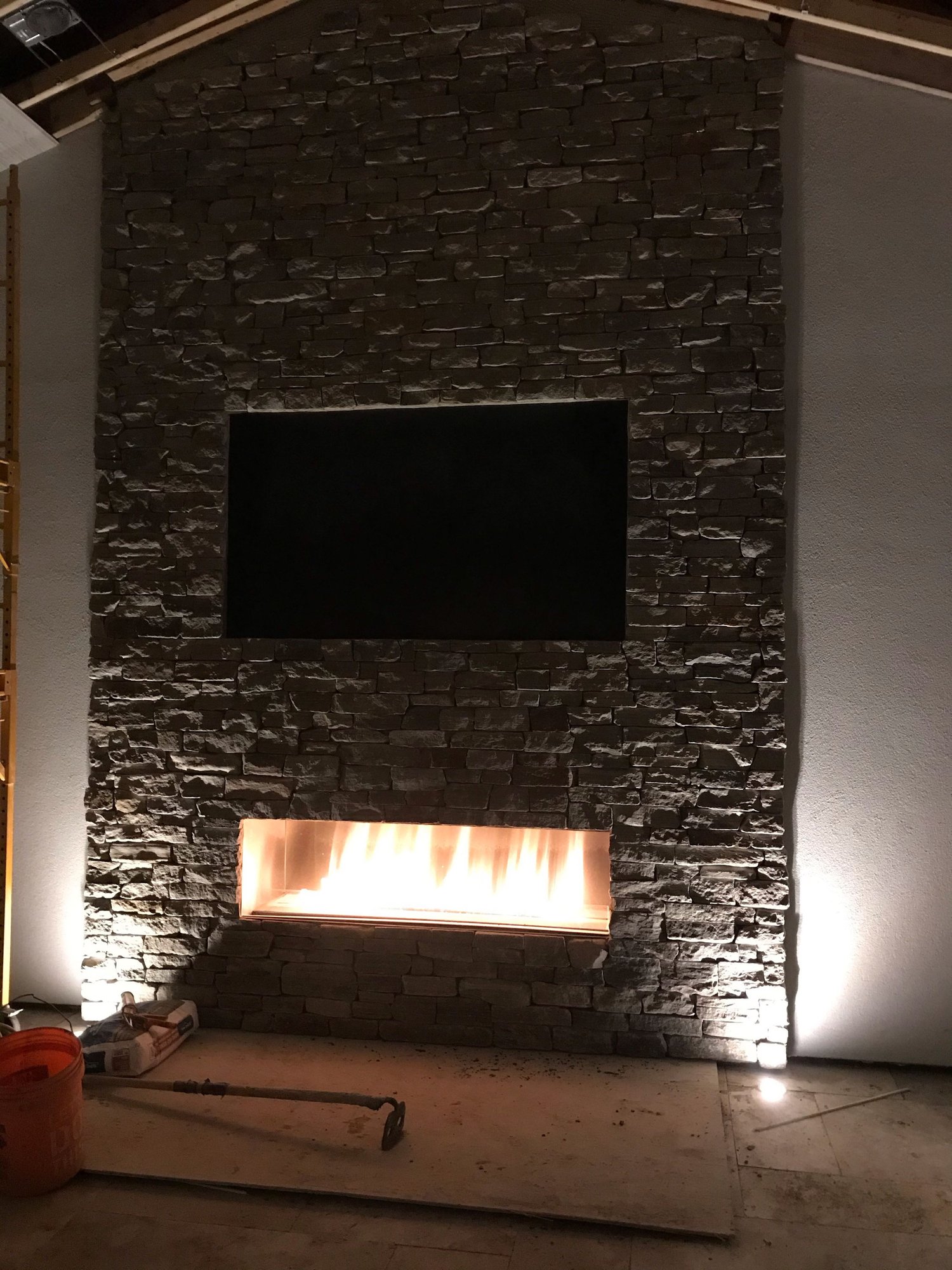 Cultured stone installation Syracuse dark ledgestone fireplace wall with linear fireplace