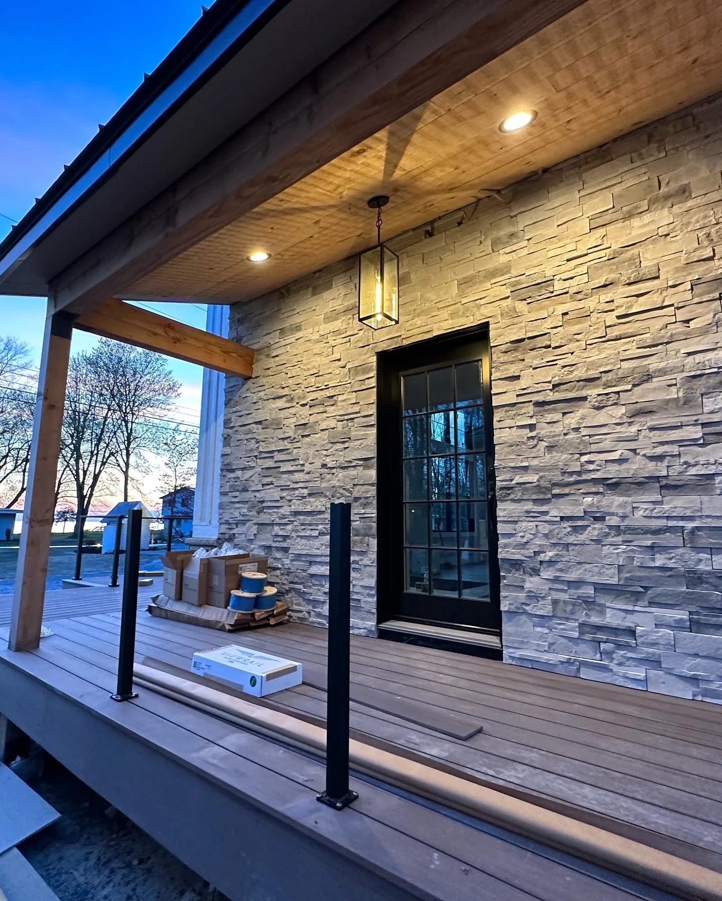 Deck installation Syracuse with composite decking next to a stone veneer wall