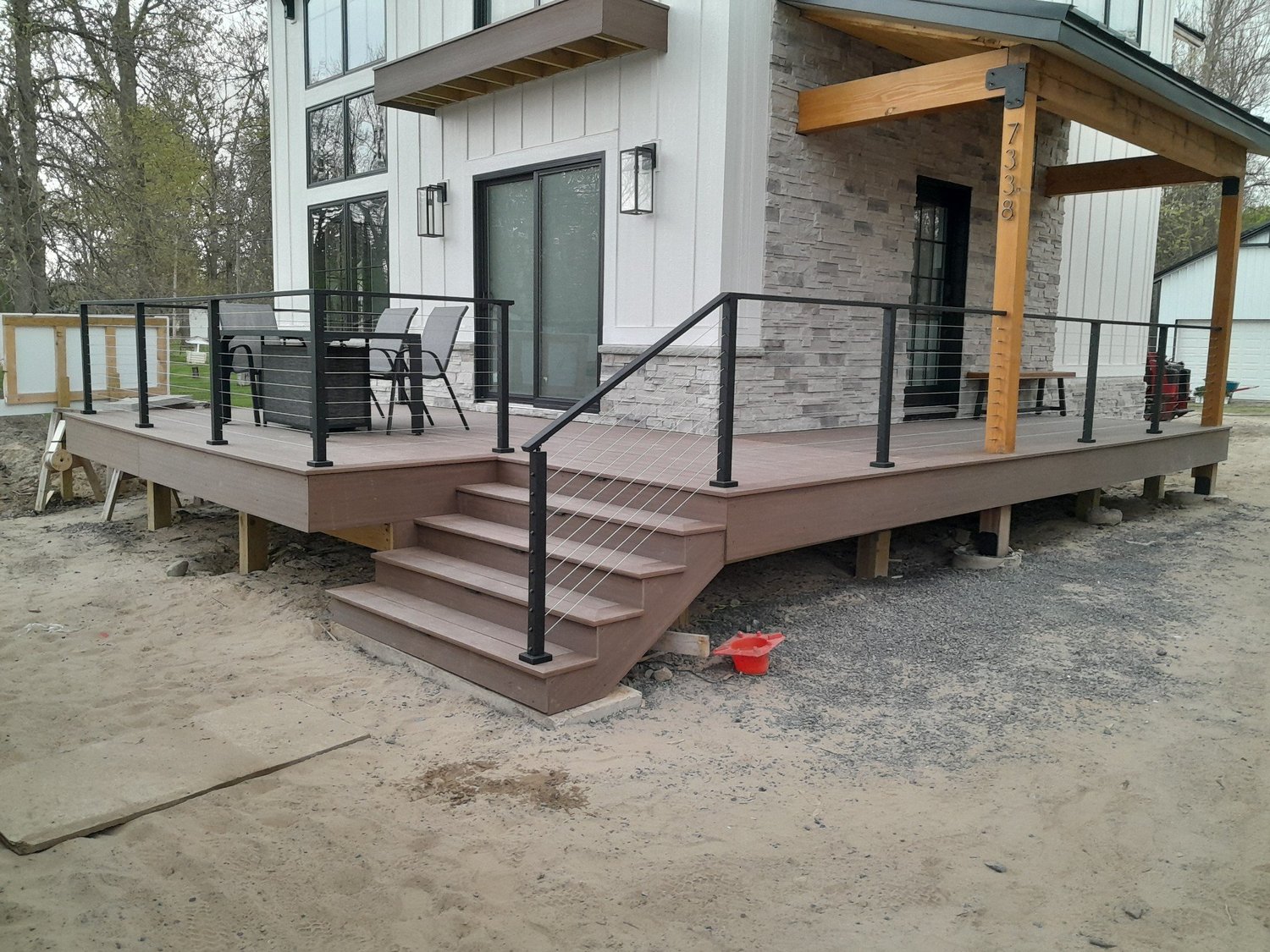 Deck builder Syracuse NY new composite deck with metal railing and stairs on a modern farmhouse