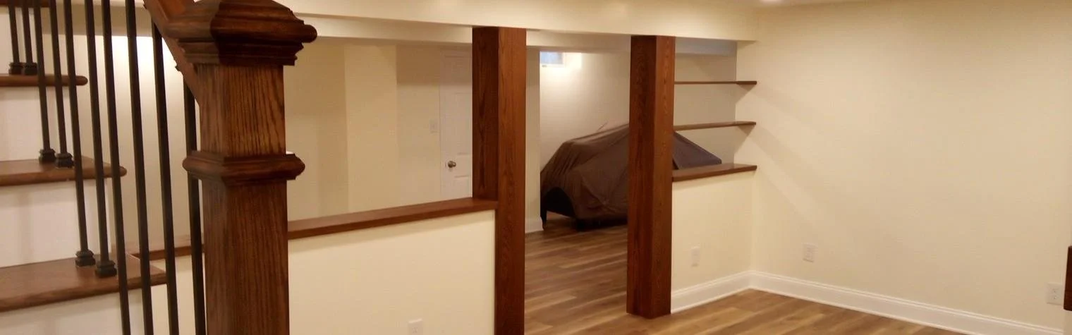 Interior view of a room with wooden staircase, wooden posts, and beige walls.