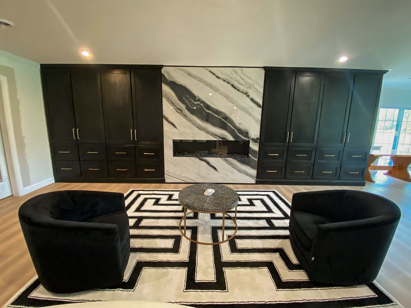 Basement remodeling Syracuse with modern marble fireplace wall and custom black cabinets