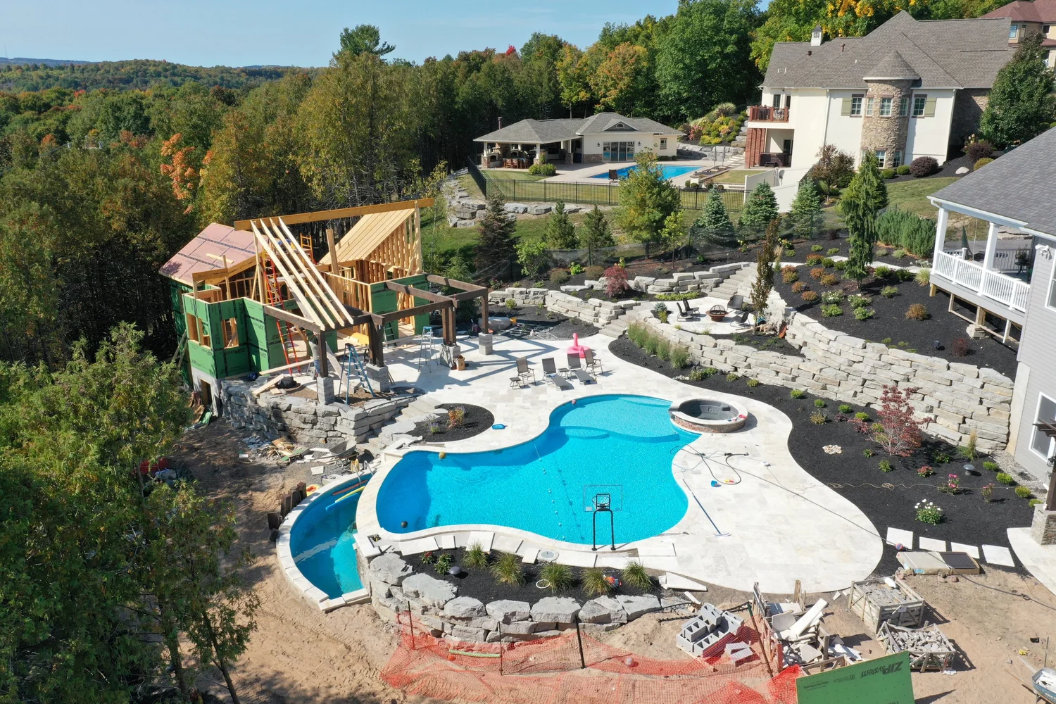 Pool house builder Central NY aerial view of pool house framing beside a new pool and landscaping