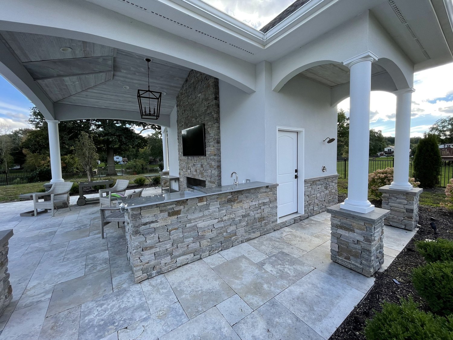 Pool house construction Syracuse with stone veneer columns, outdoor kitchen and fireplace