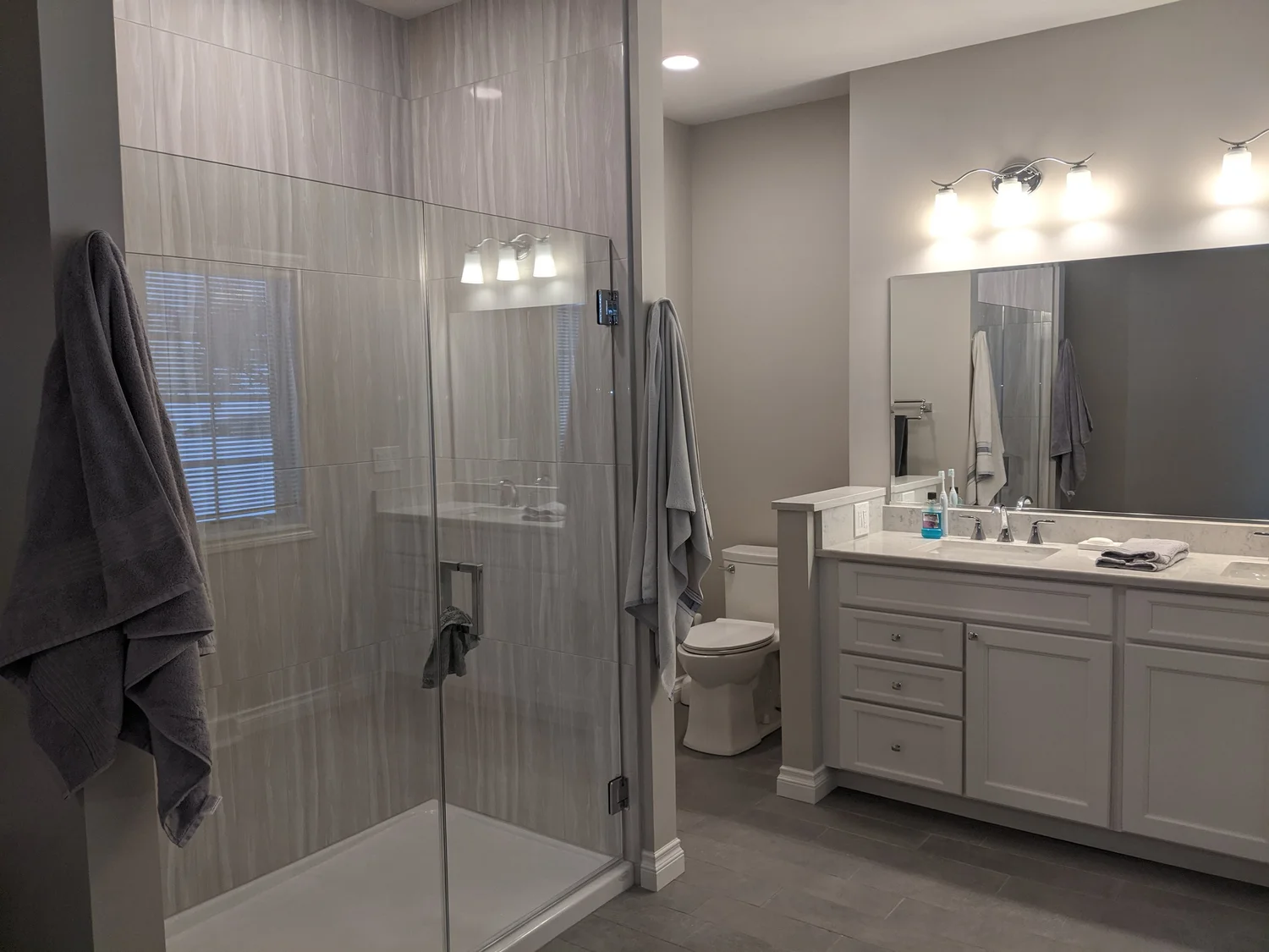 Bathroom remodel Syracuse NY glass walk-in shower with gray tile and double vanity