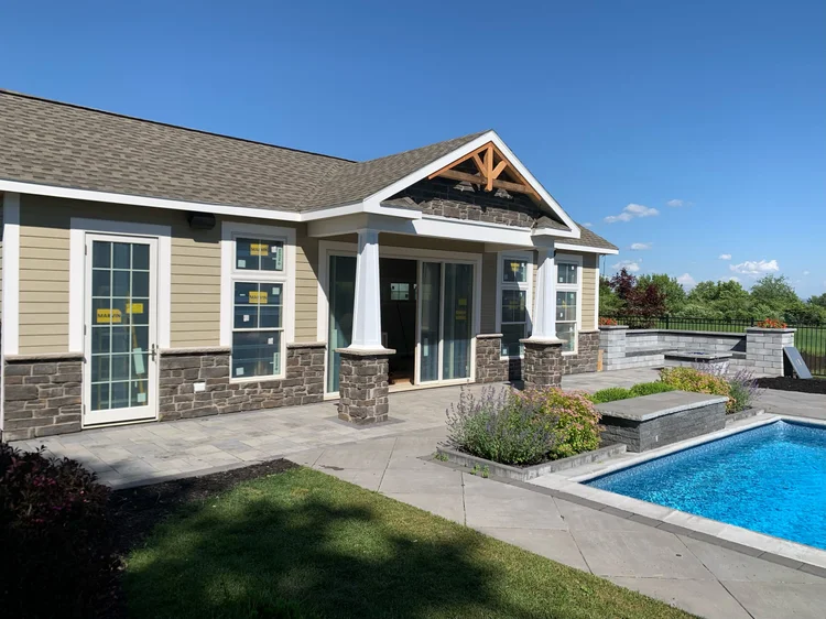 Pool house builder Syracuse custom pool house with stone columns next to in-ground pool