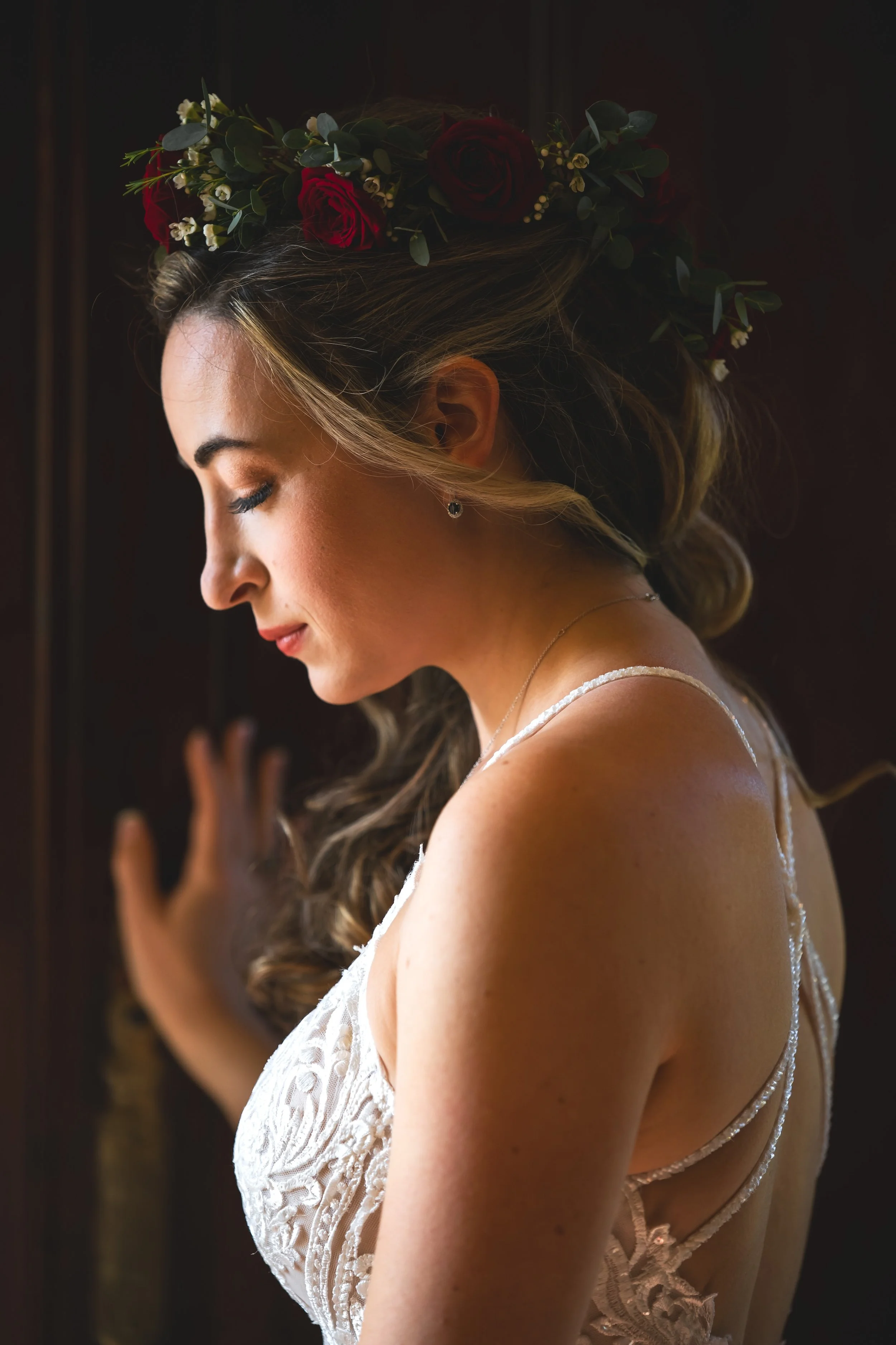 Bride in wedding dress with flowers in hair looking down at FEAST at Round Hill Wedding Venue in Fall