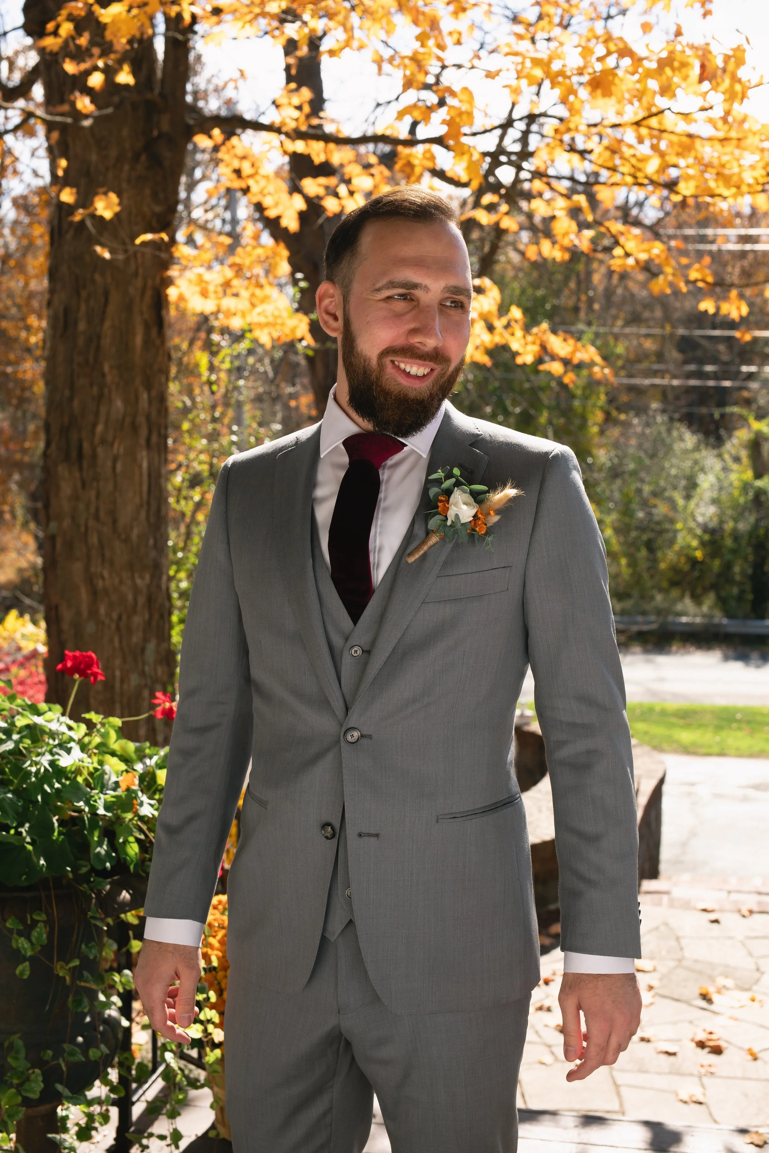 Groom in suit smiling outside FEAST at Round Hill Wedding Venue in Fall