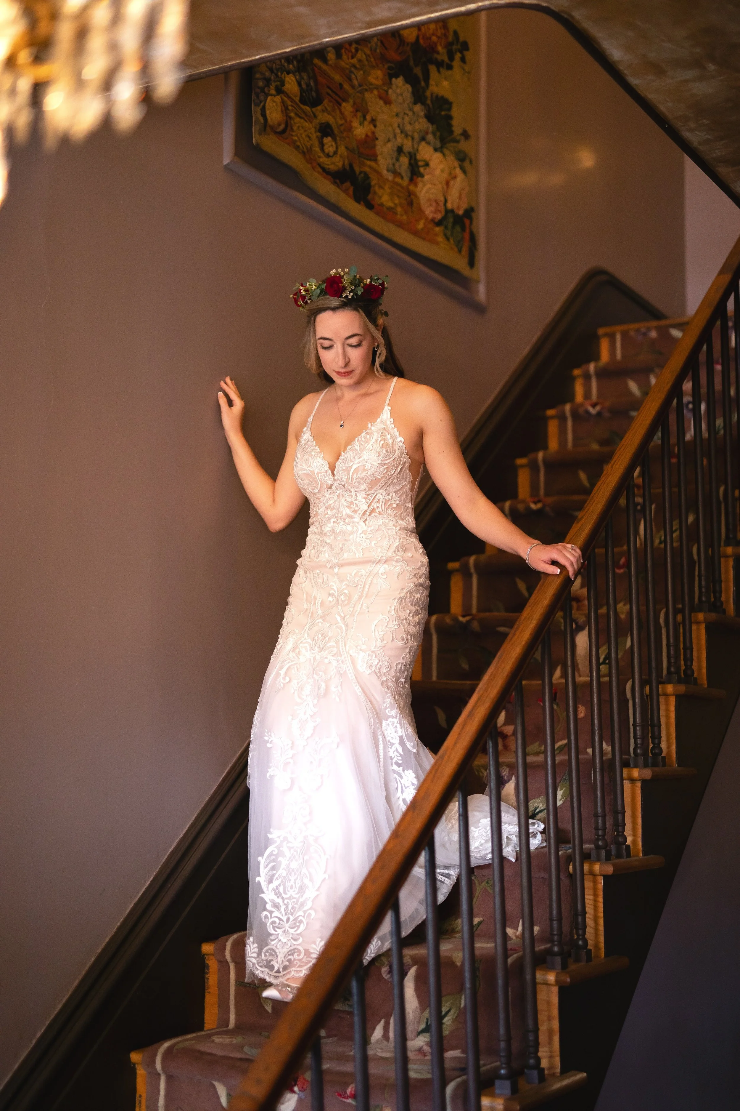 Bride in wedding dress with flowers in hair coming down stairs inside entrance to FEAST at Round Hill Wedding Venue in Fall
