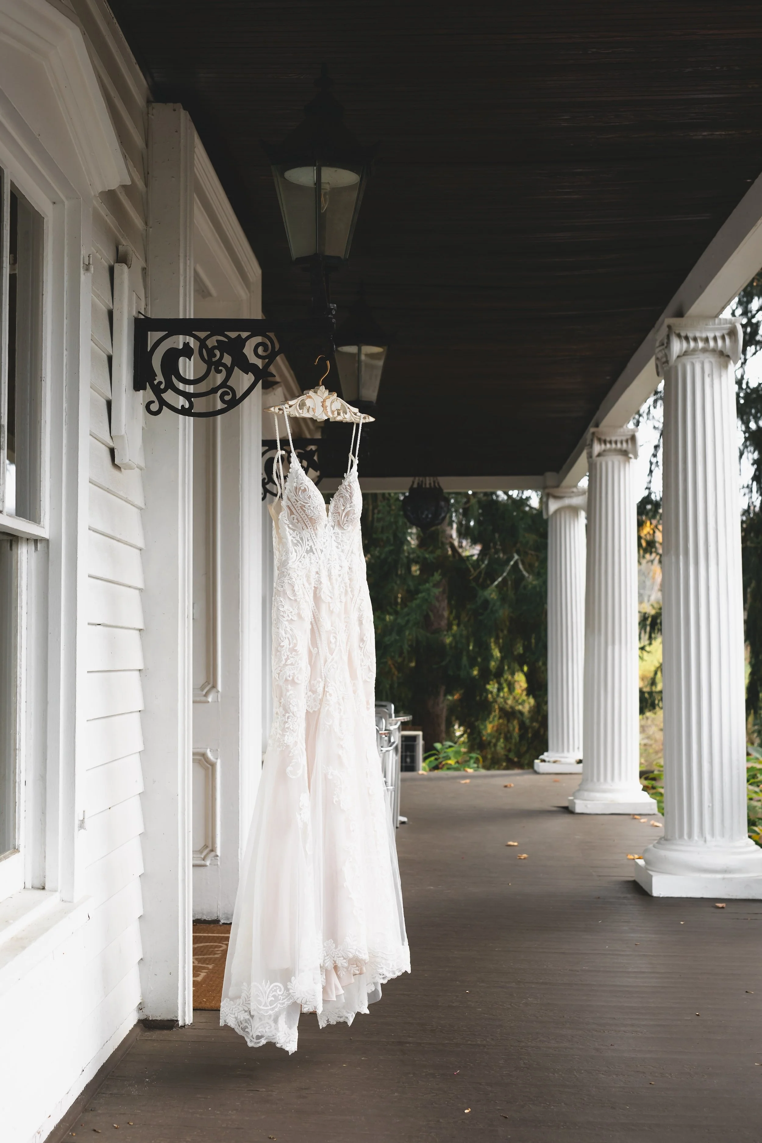 Wedding dress on hanger hanging on porch of FEAST at Round Hill