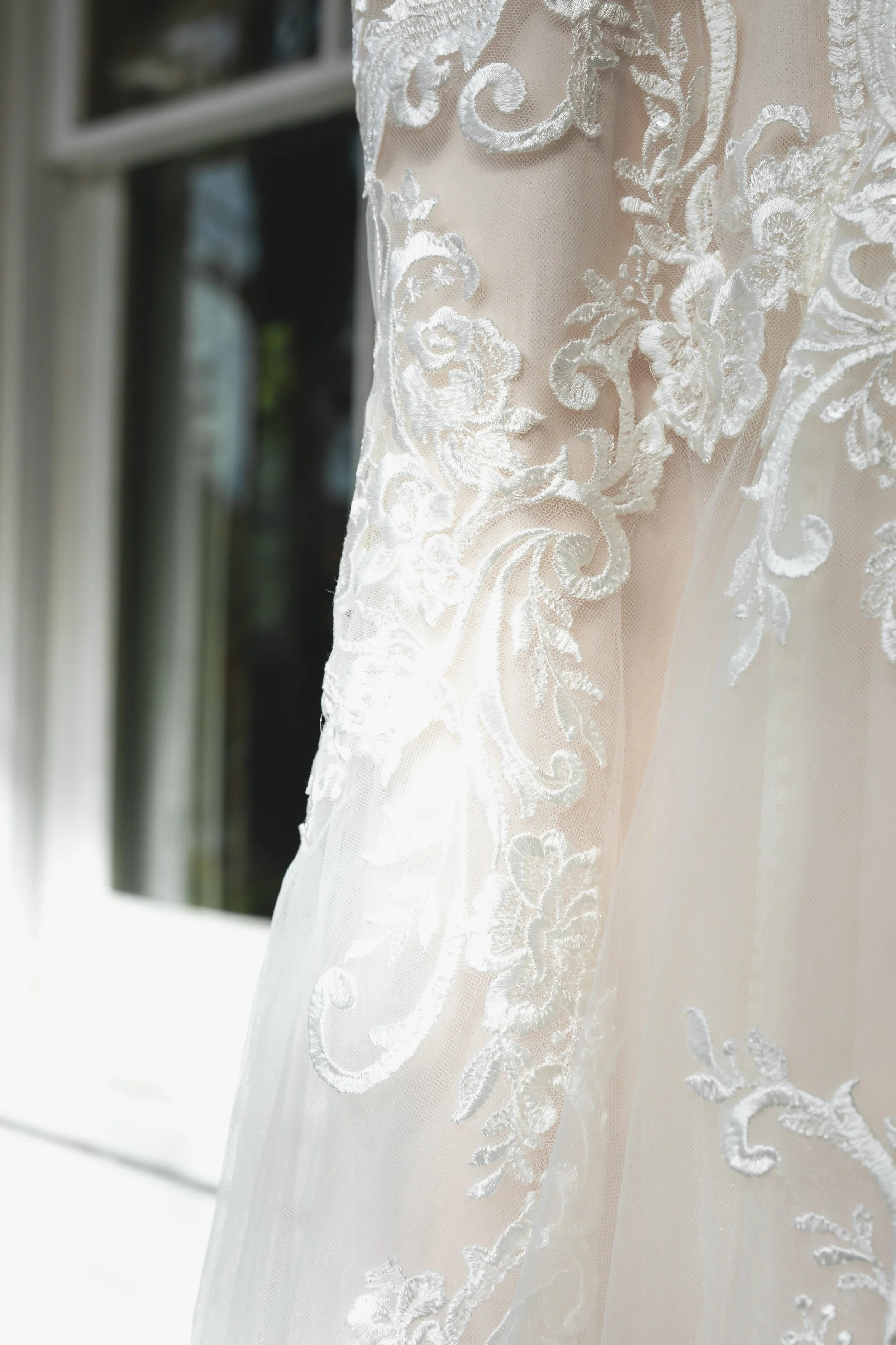 Details of Wedding dress hanging next to window at FEAST at Round Hill