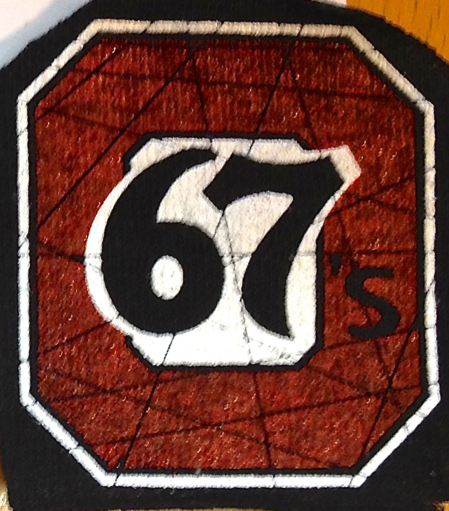 The 67’s red is printed directly on the black background.
