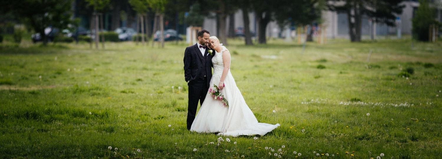Ein Brautpaar steht in einem grünen Park mit Bäumen. Der Bräutigam trägt einen schwarzen Anzug in Darmstadt – von pixelfeder