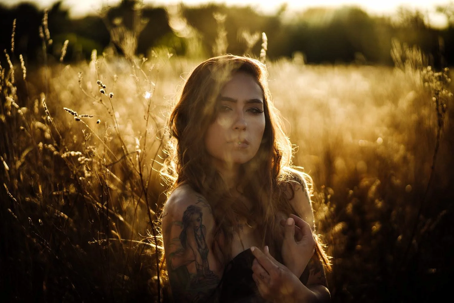 Portrait einer jungen Frau bei Sonnenuntergang im Feld auf dem Boden sitzend mit Tattoos in Darmstadt – von pixelfeder