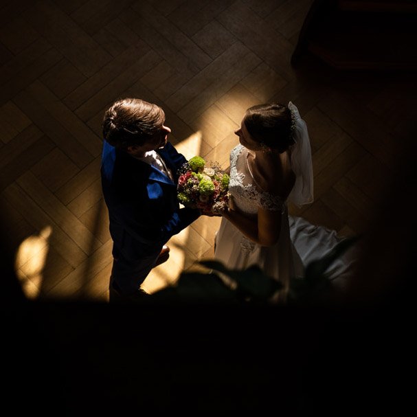 Ein Brautpaar bei der Hochzeitszeremonie, das sich gegenseitig anschaut, während der Bräutigam dem Brautstrauß hält.