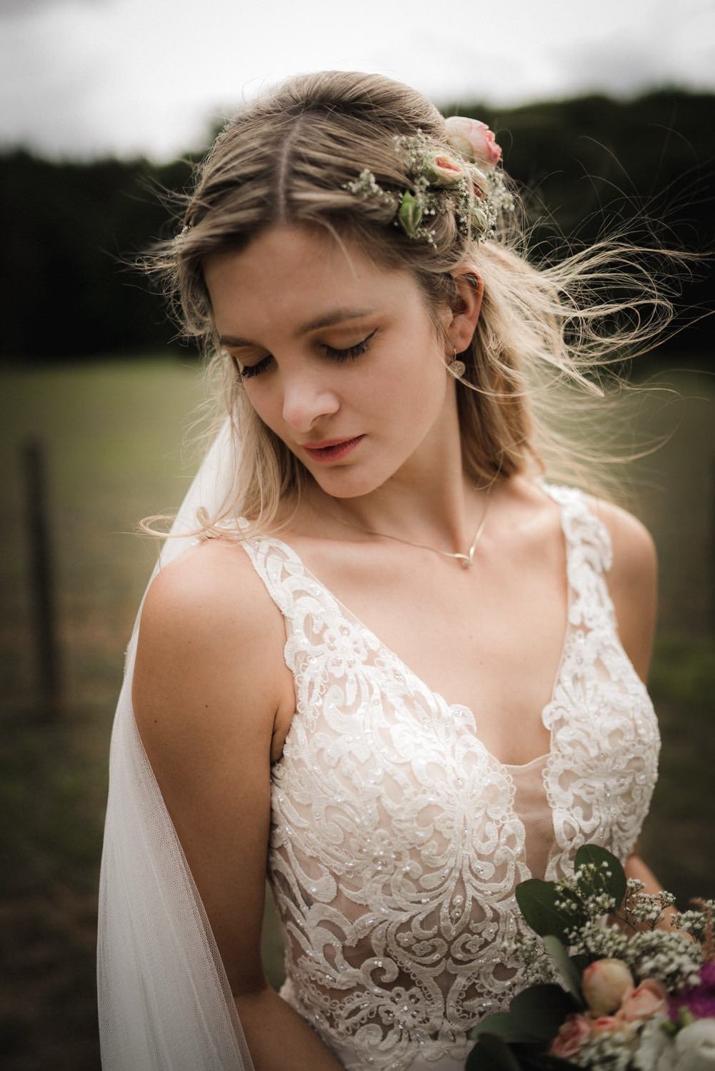Junge Frau in einem weißen Brautkleid mit Spitze, mit Blumen im Haar, hält einen Blumenstrauß in Darmstadt – von pixelfeder