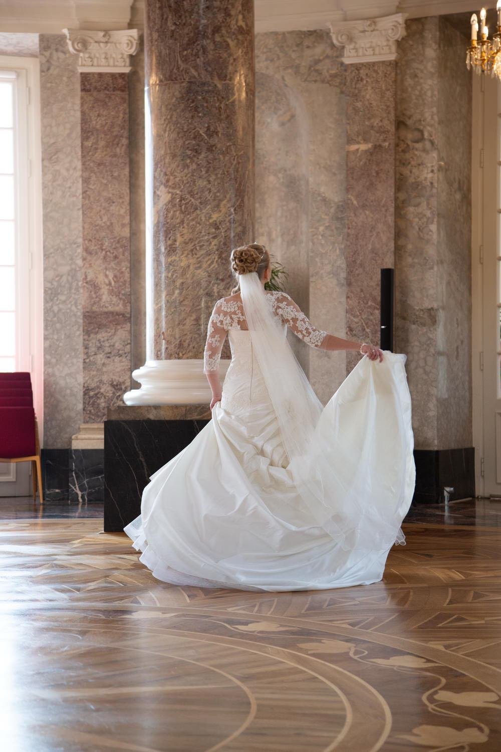 Braut in Hochzeitskleid dreht sich in einem eleganten Saal mit Marmorsäulen und Holzboden in Darmstadt – von pixelfeder