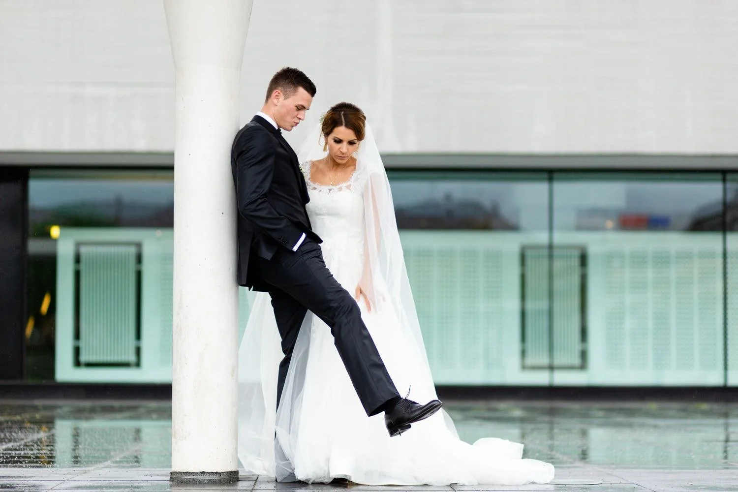 Ein brautpaar in Hochzeitskleidung steht vor einem modernen Gebäude in Darmstadt – von pixelfeder