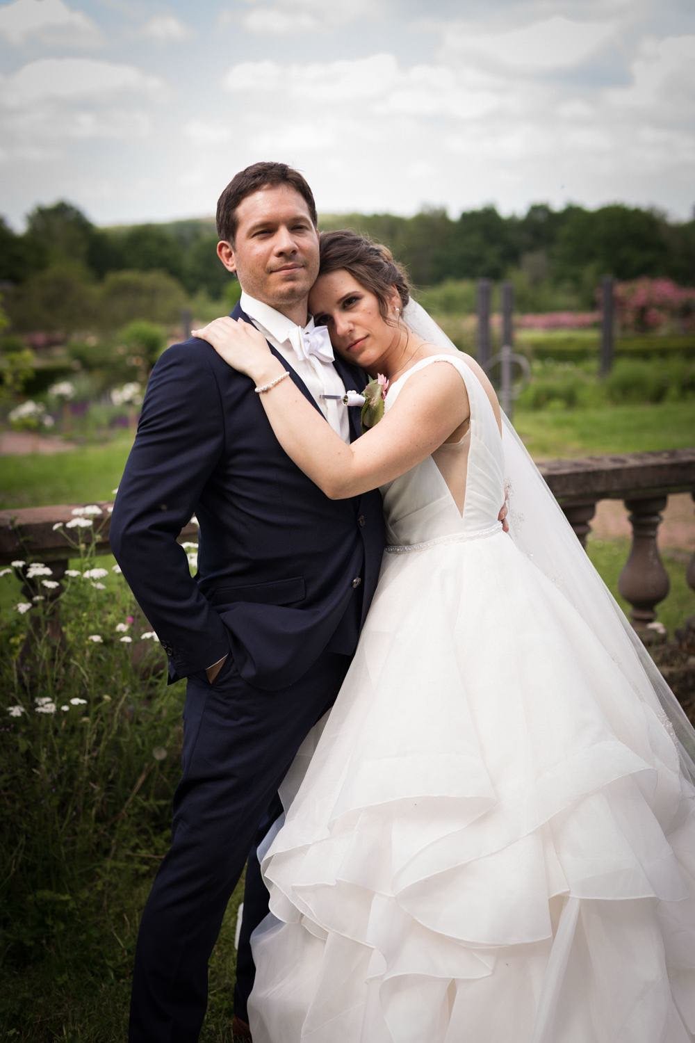 Brautpaar beim paarshooting steht im Freien, umgeben von Pflanzen und Blumen in Darmstadt – von pixelfeder