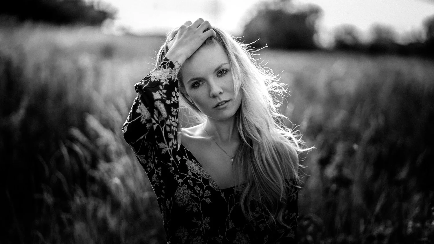 Portrait einer Frau mit lockigen, blonden Haaren in einem Kleid im Feld – Schwarz-Weiß von pixelfeder