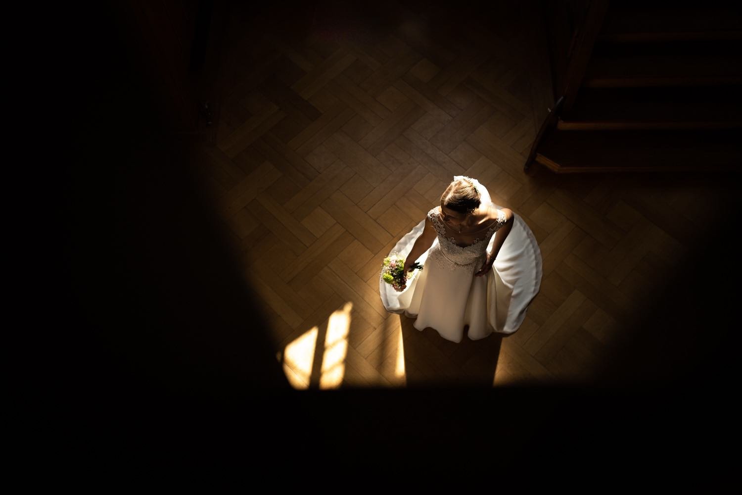 Eine Braut in einem weißen Hochzeitskleid steht im Licht, fotografiert von oben in Darmstadt – von pixelfeder
