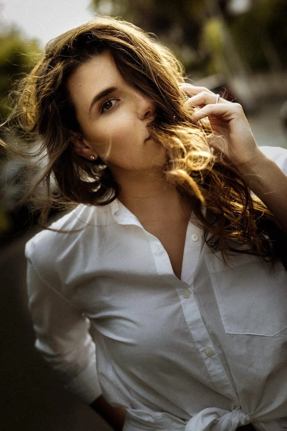 Junge Frau mit braunen, lockigen Haaren, weiße Hemd, Hochformat, sinnliches Portrait bei Sonnenlicht, unscharfer Hintergrund, natürlicher Look