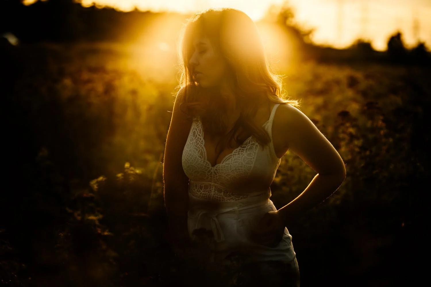 Portrait einer Frau mit lockigen, braunen Haaren bei Gegenlicht bei Sonnenuntergang – von pixelfeder
