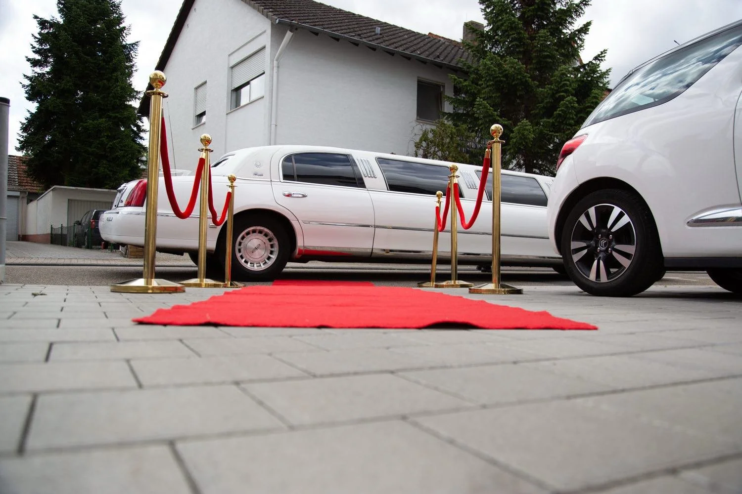 Ein roter Teppich und Absperrpfosten vor einem weißen Limousine in darmstadt - pixelfeder