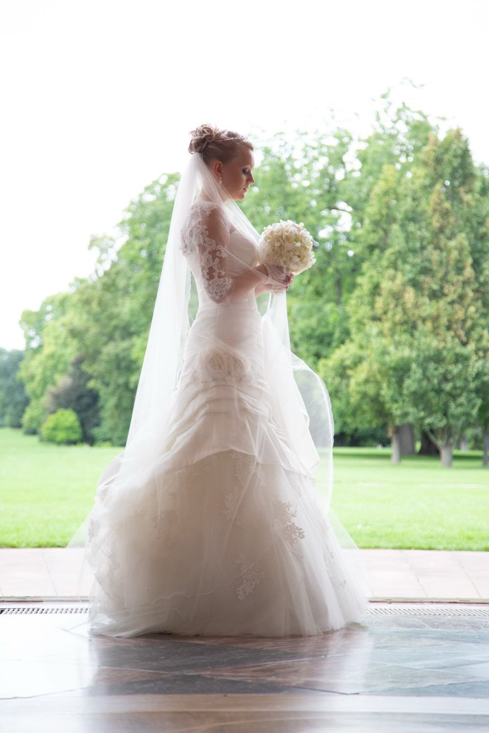 Braut im Schloss mit Blumenstrauß vor Fenster mit Blick auf den Park in Darmstadt – von pixelfeder